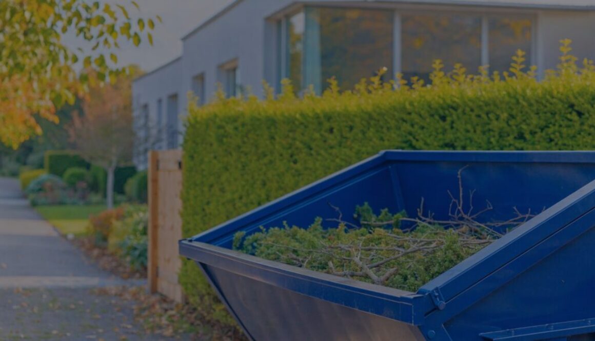 Blaue Mulde für Grünschnitt mit Heckenschnitt und Ästen vor einem Wohnhaus