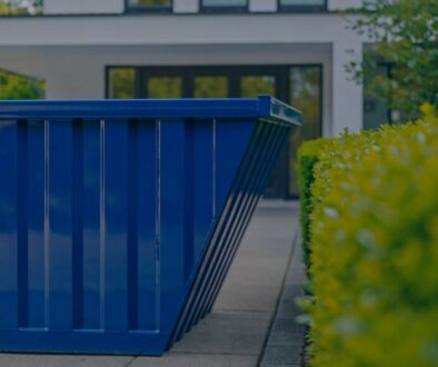 Leere blaue Mulde vor einem Wohnhaus - Müllmulde Kosten für Restmüll und Mischmüll