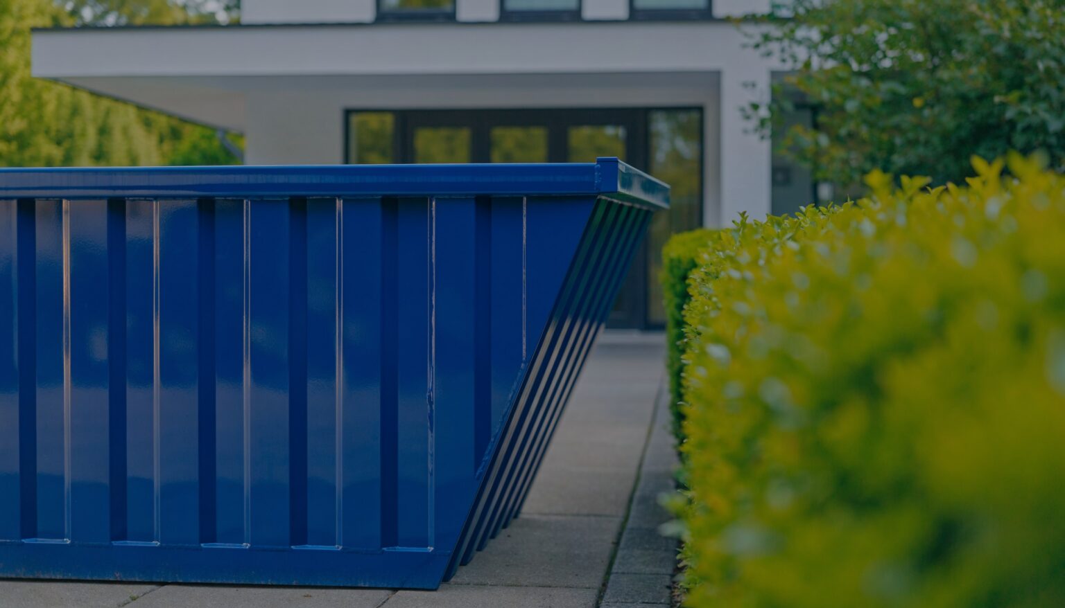 Leere blaue Mulde vor einem Wohnhaus - Müllmulde Kosten für Restmüll und Mischmüll