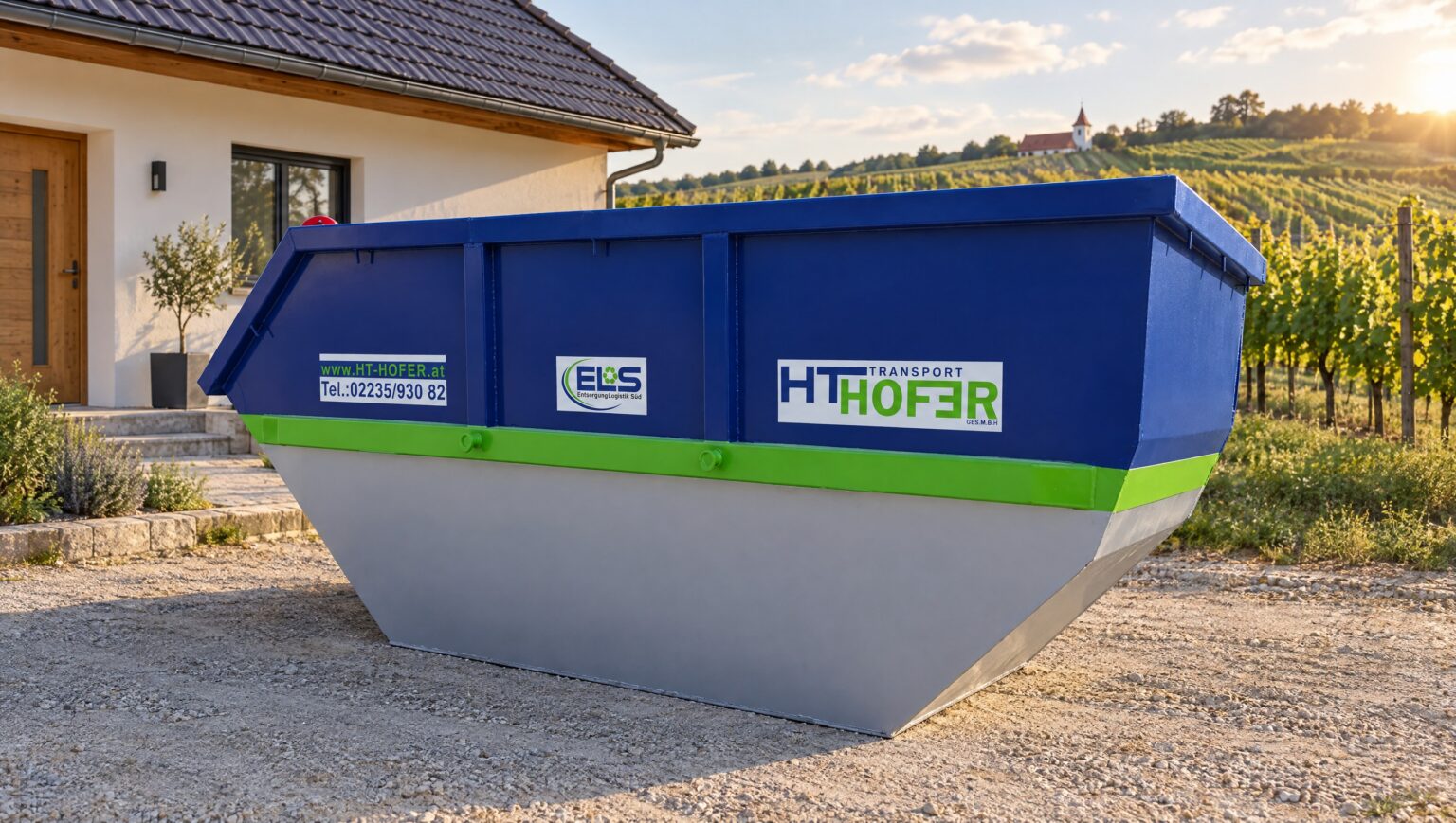 Leere blaue Absetzmulde auf einer gepflasterten Einfahrt vor einem Einfamilienhaus - Mulde mieten in Niederösterreich